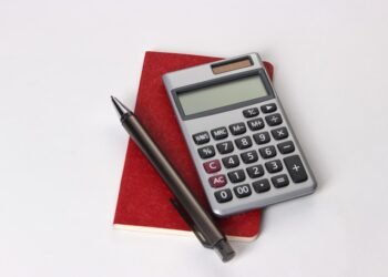 Calculator, notebook, and financial planning materials representing retirement contribution planning