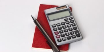Calculator, notebook, and financial planning materials representing retirement contribution planning